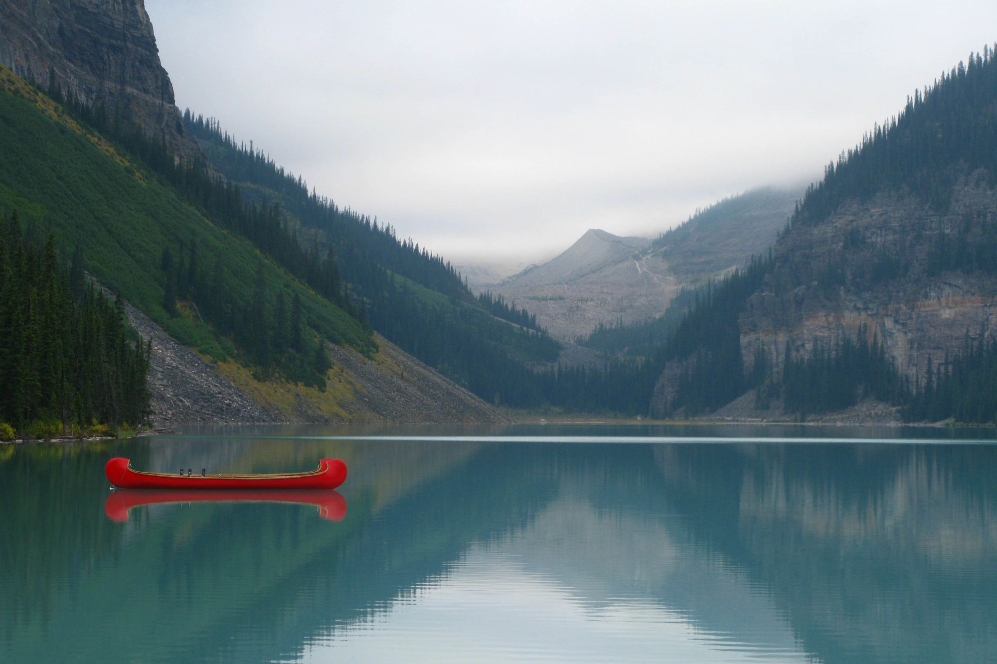 Red canoes on a dock at Lake Louise with mountains behind