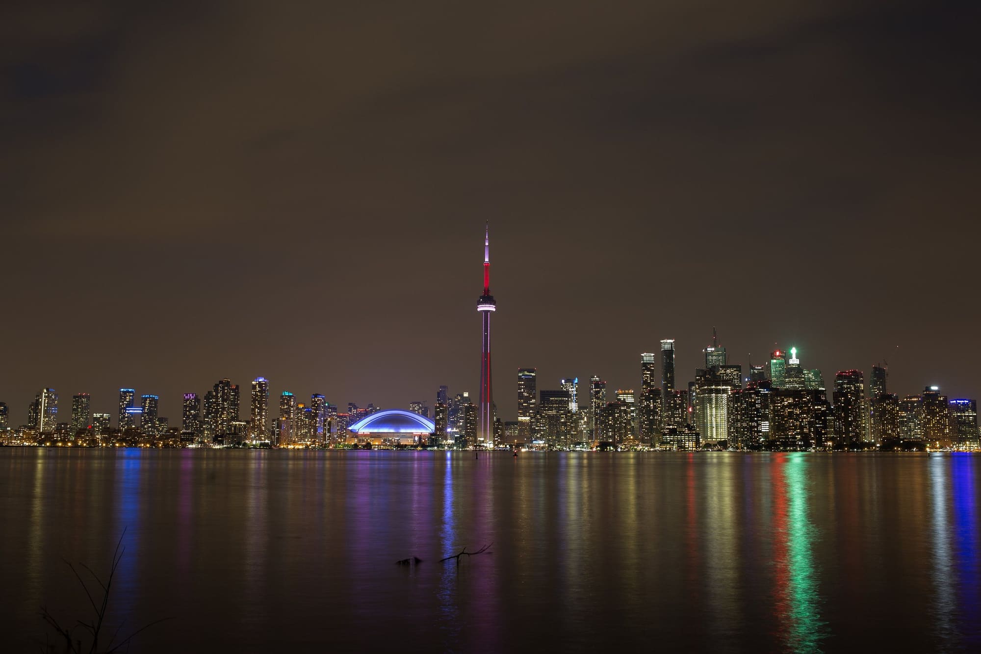 Toronto's skyline and the CN Tower lit up at night across the water